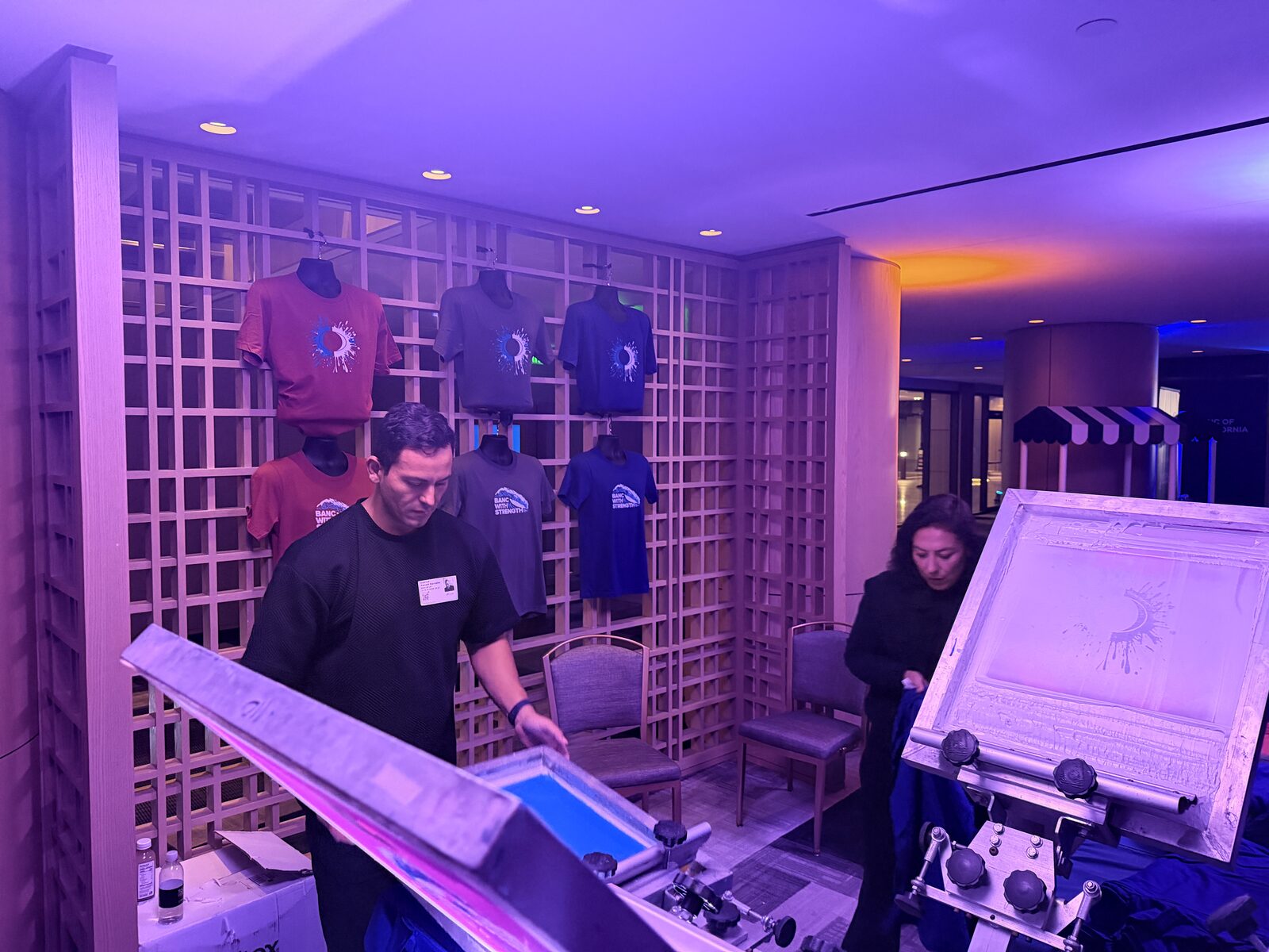 Wall of printed shirt options displayed at a live printing station