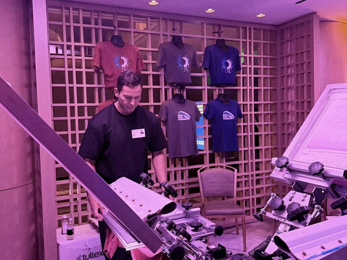 Merch Troop t-shirt press station styled for a wedding with folded tees ready for guests